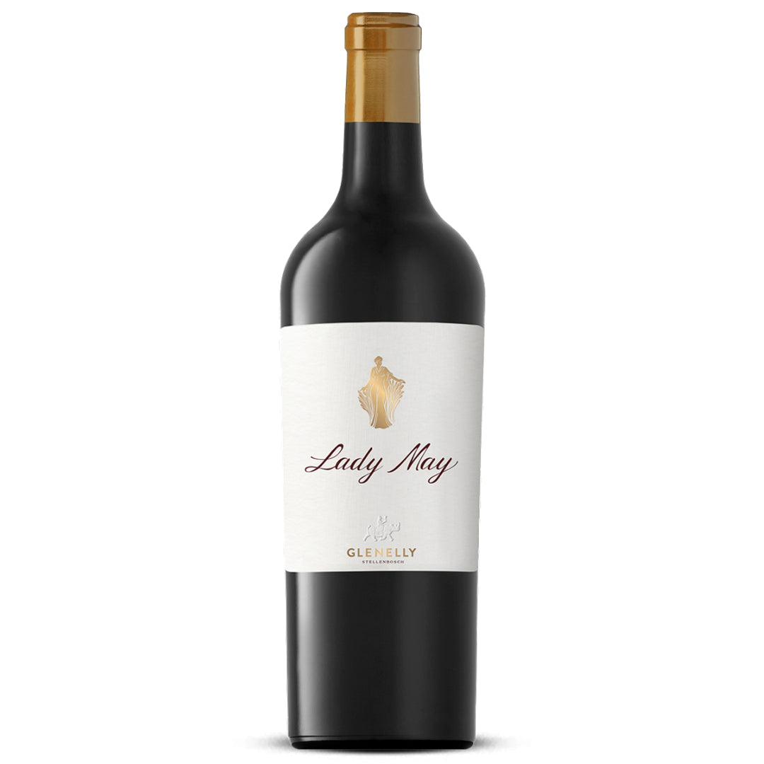 Bottle of Glenelly Estate Lady May 2017 with crystal stemware, fresh herbs, and candlelight on a dark wood table.
