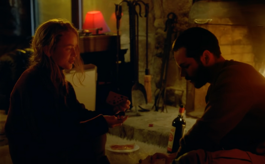 Scene from Taylor Swift's All Too Well: The Short Film, where a bottle of Ercole Barbera del Monferrato appears near the fireplace during an intimate pizza and card-playing moment between the lead characters.