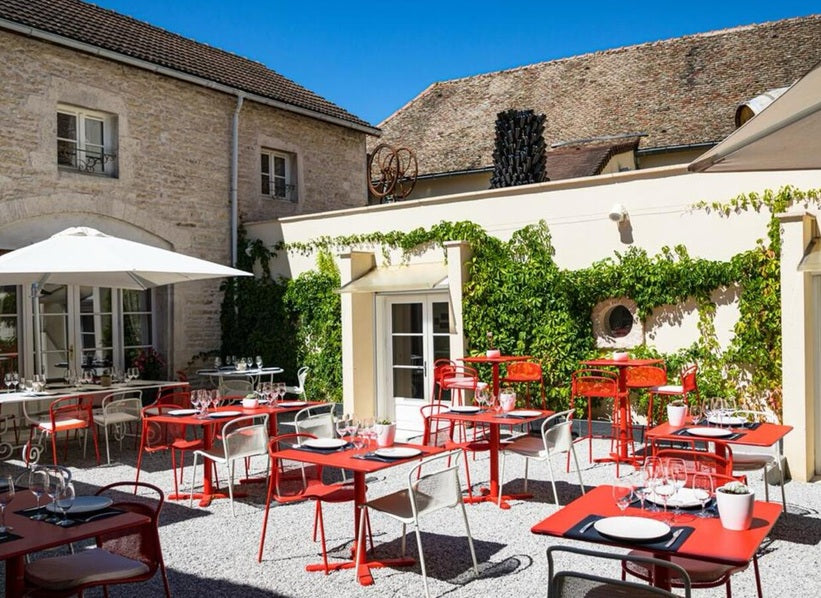 Maison Olivier Leflaive courtyard terrace in Burgundy with red café tables and stone buildings